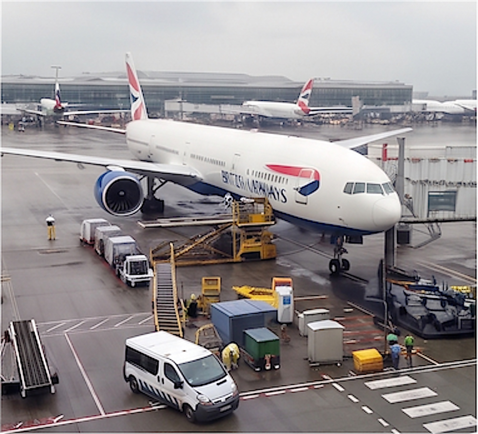 Boeing 777 no portão, sendo atendido no pátio molhado